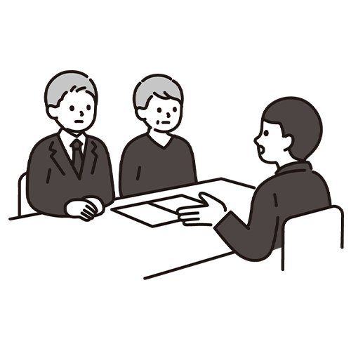 机を囲んで話し合う3人の人物